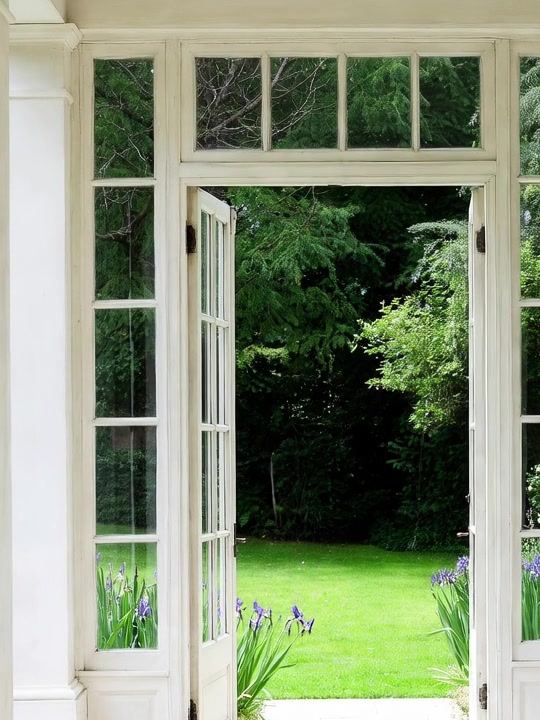 Tall white garden doors just opening onto a lawn.