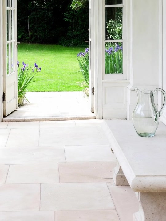 A pale stone bench with one clear glass pitcher.